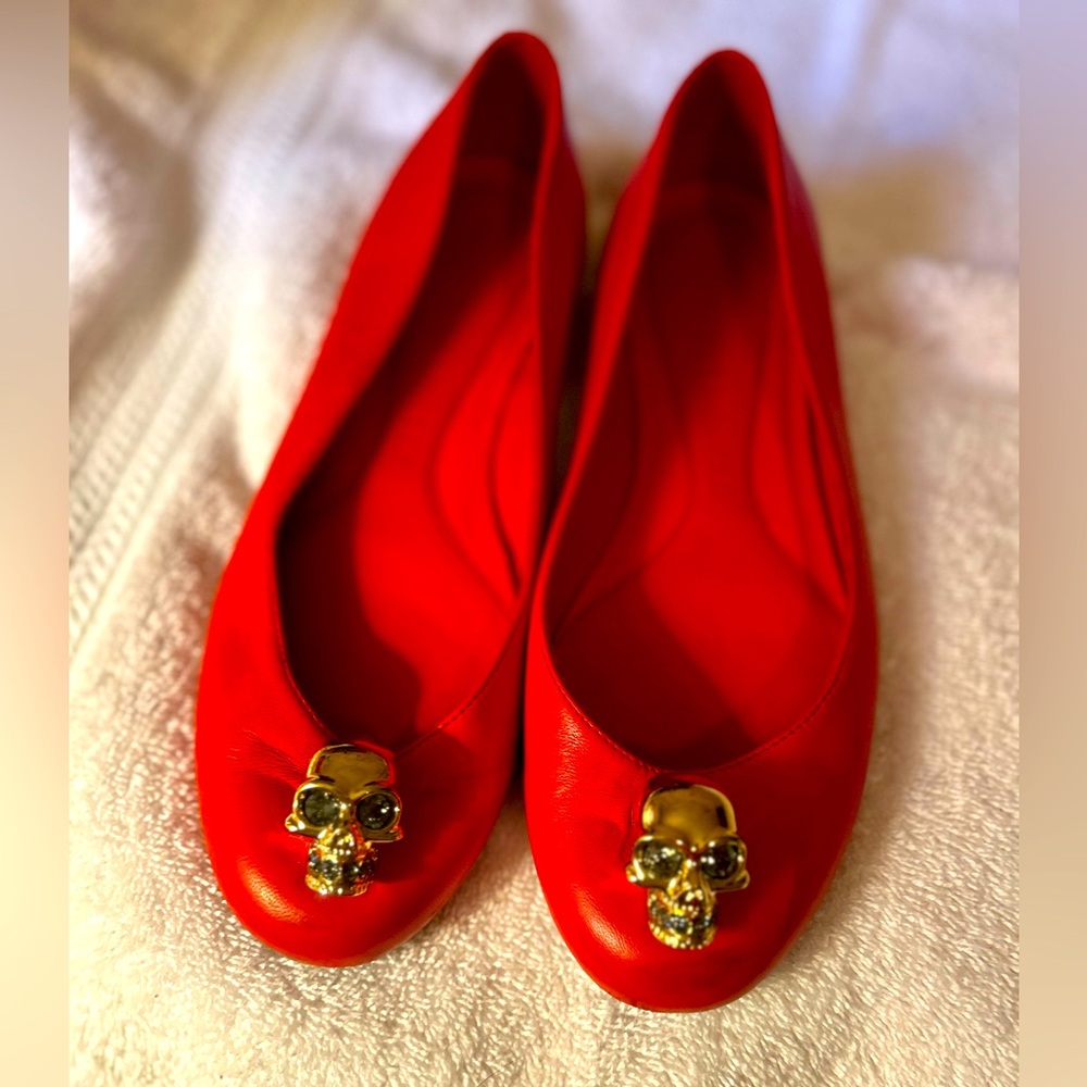 Alexander McQueen red ballet flats with golden skull detail.